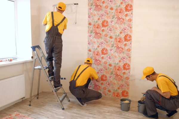 Brigade of builders hang wallpaper in the apartment.